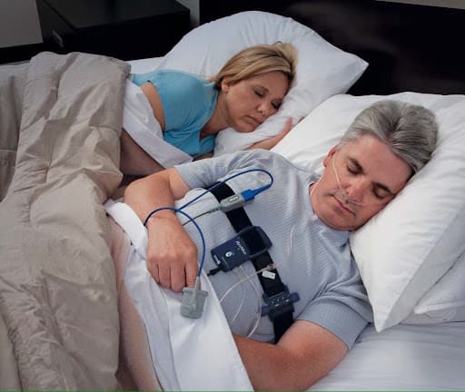 Paciente na cama com o equipamento da polissonografia domiciliar